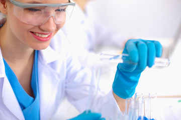 Woman researcher is surrounded by medical vials and flasks