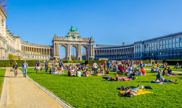 People are relaxing next to cinquantenaire monument in brussels during first sunny weekend in March.