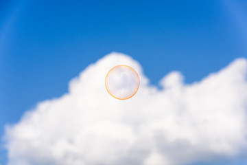 A big orange soap bubble flying up into the blue sky