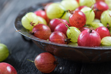 Fresh green and red gooseberry in rustic bowl