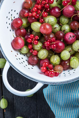 Fresh green and red gooseberry in rustic colander