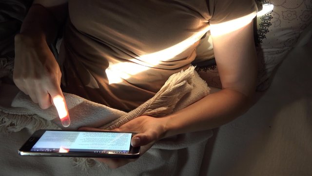 Frau benutzt Tablet Computer liegend auf dem Sofa
