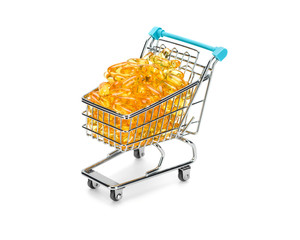 Shopping cart filled with yellow omega 3 fatty acids capsules on pure white background. Healthy...