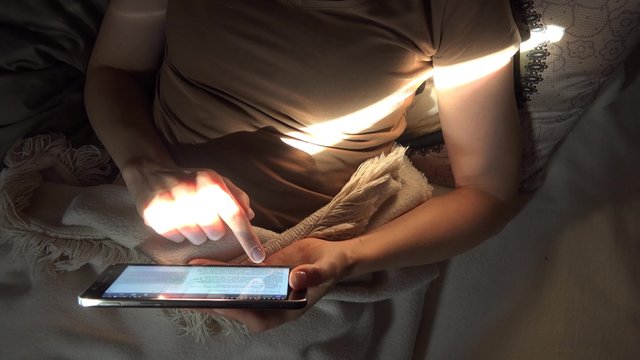 Frau benutzt Tablet Computer liegend auf dem Sofa