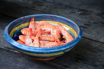 boiled tiger shrimps in a earthenware bowl on rustic dark wood