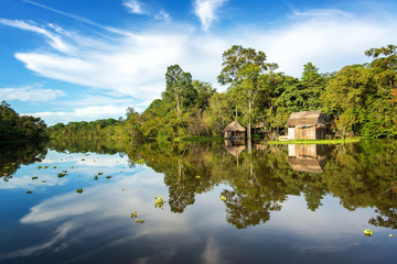 Small wooden shack in the Amazon rain forest with a beautiful reflection on the Yanayacu River near Iquitos, Peru - obrazy, fototapety, plakaty