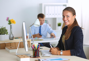 Fashion designers working in studio sitting on the desk