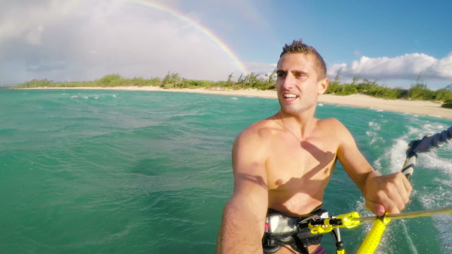 Young Man Kite Boarding in Ocean with Rainbow in Background. Extreme Summer Sport POV
