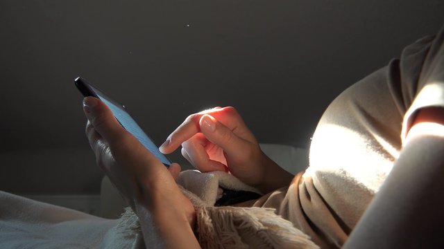 Frau benutzt Tablet Computer liegend auf dem Sofa