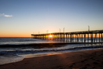 Virginia Beach fishing pier at sunrise as seen in silhouette.