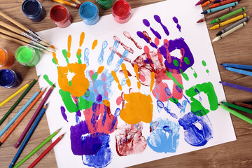 Child handprints or hand prints and art equipment on a school desk with paint arts and crafts...