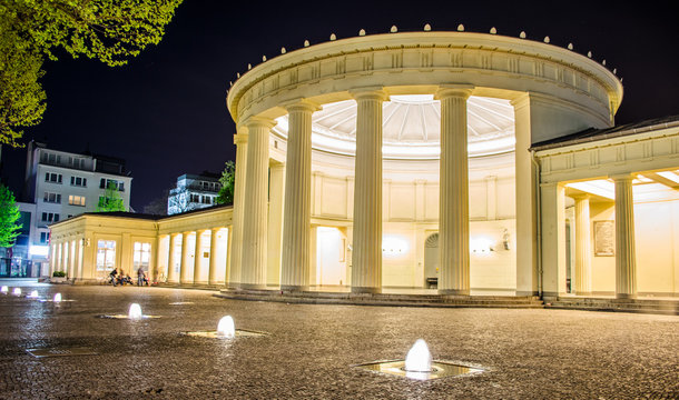 People are sitting in front of illuminated elisenbrunnen in german Aachen.