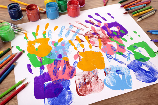 Child handprints or hand prints and art equipment on a school desk with paint arts and crafts equipment photo