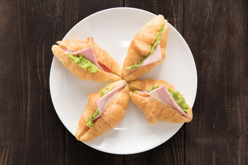 Croissant with parma ham and lettuce on wooden table