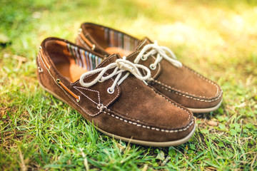 Modern brown leather mens shoes, elegant summer moccasins in grass. Men fashion, men accesories and footwear.
