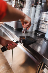 Barista using a tamper to press ground coffee