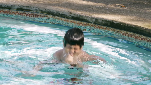 Boy Dunks Head in Shallow Pool Water. Boy dunks in shallow pool water, Hispanic origin; six years old.