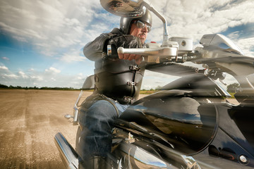 Biker in helmet and leather jacket racing on the road on a motorcycle.