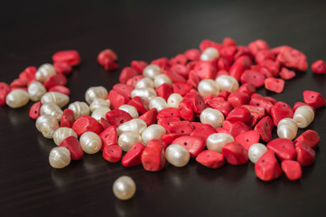 The scattered beads of red and white color on a dark wooden background