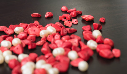 The scattered beads of red and white color on a dark wooden background