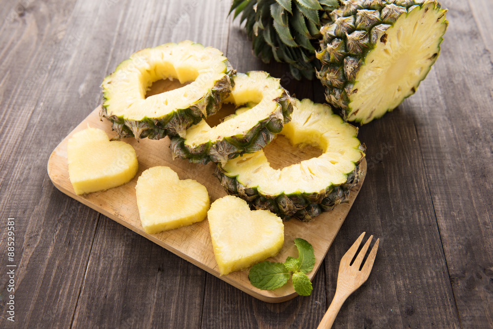 Wall mural pineapple slices with a cut in the shape of hearts on wooden bac