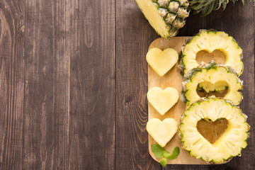 Pineapple slices with a cut in the shape of hearts on wooden bac