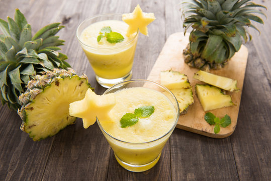 Pineapple smoothie with fresh pineapple on wooden table