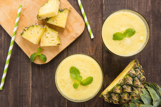 Pineapple smoothie with fresh pineapple on wooden table