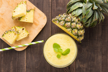 Pineapple smoothie with fresh pineapple on wooden table