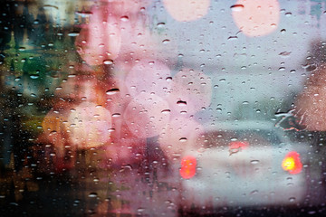 Driving in rain, raindrops on car window with light bokeh, rainy