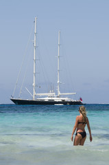 Blond girl looks sailing ship sea blue and green to the beach