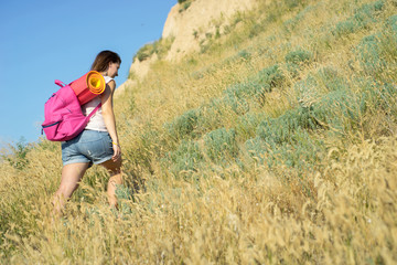 a woman with a backpack climbs up the hill