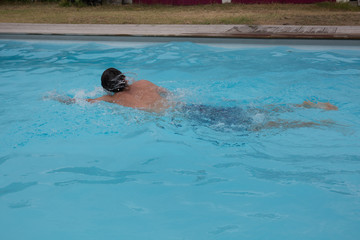 A Teenager swims in a pool on summertime