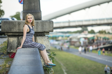 Fototapeta na wymiar Beautiful young lady sits on the quay Vistula river in Krakow.