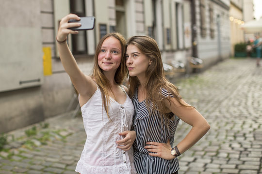  Selfie. Teenage girls take pictures of themselves on the smartphone on the street.
