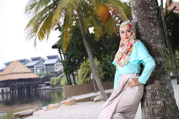 high fashion muslim women sitting at wooden white chair with beach background