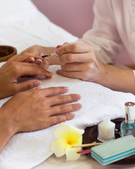 Obraz na płótnie Canvas Woman in nail salon receiving manicure by beautician
