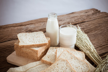 glass of milk and whole wheat bread on the wooden board
