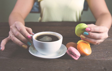 A girl holding a cup of coffee with macaroon