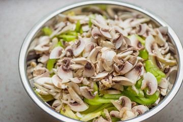Sliced champignon mushrooms and green pepper in a metallic dish