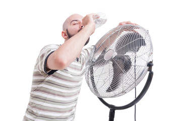 Man drinking water near blowing fan