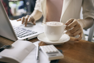 Fototapeta na wymiar woman holding cup of coffee while working 