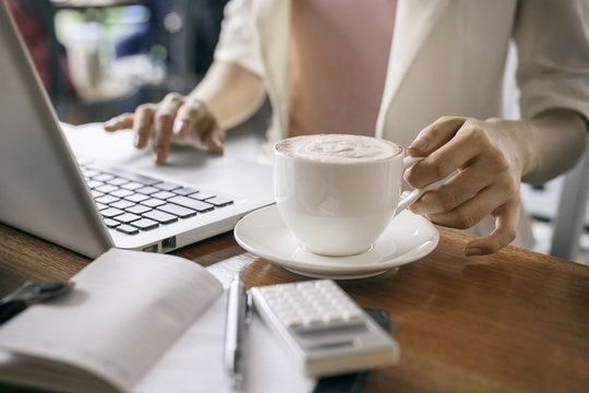 woman holding cup of coffee while working 