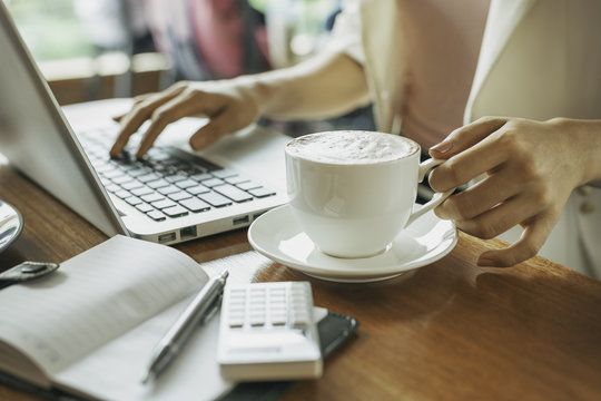 woman holding cup of coffee while working 
