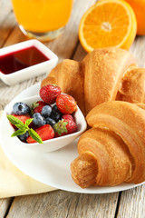 Fresh tasty croissants with berries on grey wooden background