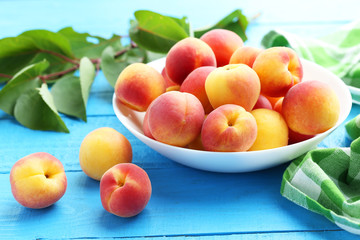 Fresh apricots in plate on a blue wooden background