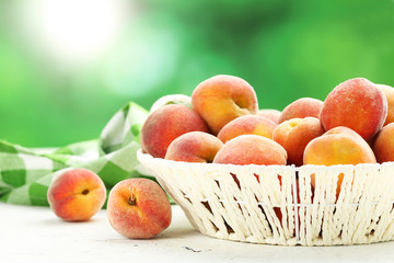 Ripe peaches fruit in basket on a white wooden background