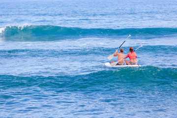 surfer les vagues assis sur paddle 