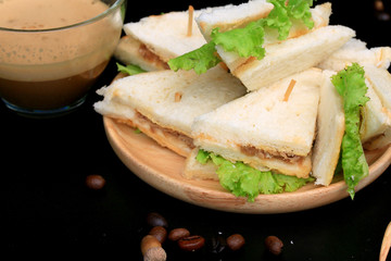 tuna sandwiches and hot coffee on black background