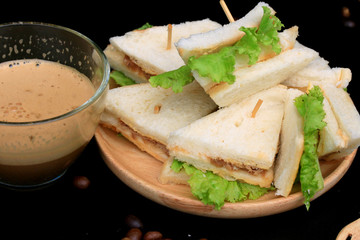 tuna sandwiches and hot coffee on black background